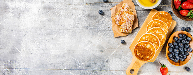 Poster - Homemade pancakes on a cutting board with honey and berries. 