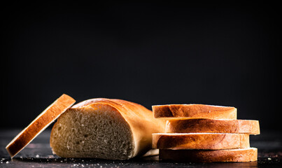 Poster - Sliced wheat bread. On a black background.