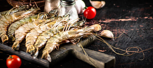 Poster - Raw shrimp on a cutting board with spices and tomatoes. 