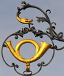 Schmiedeeisernes Nasenschild mit goldenem Posthorn gehalten von einer Schlange