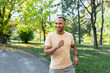 © Liubomir - Cheerful and successful hispanic man jogging in the park, man running on a sunny day, smiling and happy having an outdoor activity.