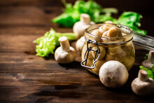 A Small Glass Jar With Pickled Mushrooms On The Table. 