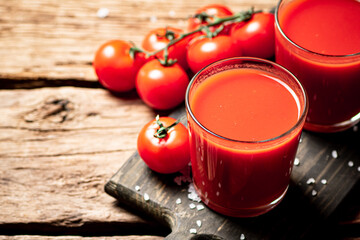 Poster - Glasses with tomato juice on a wooden cutting board. 