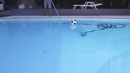 Wall Mural - Vacuuming the dirty bottom of a swimming pool. A special brush with a striped hose cleans the pool.