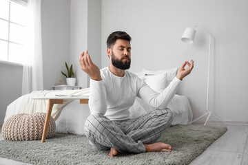 Poster - Handsome young man meditating on carpet at home