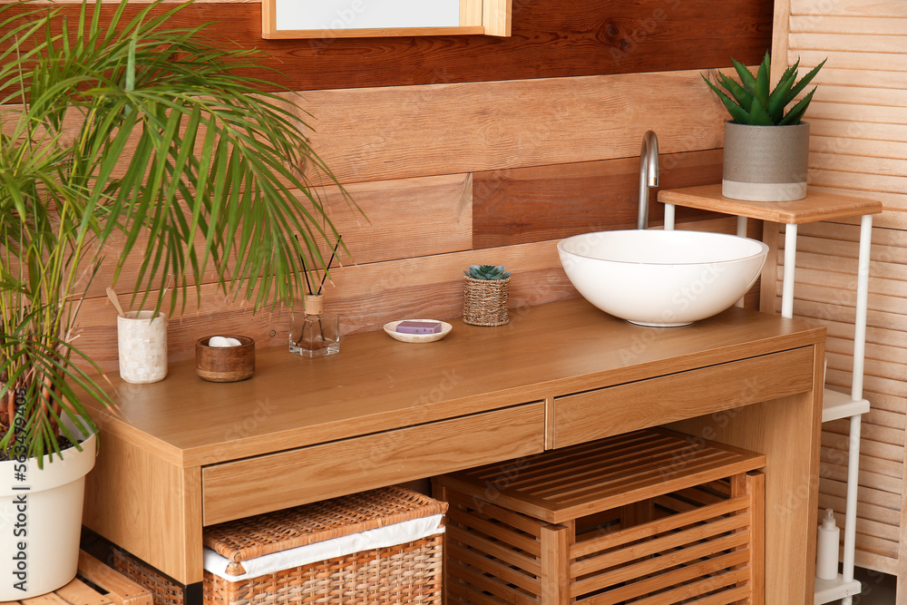 Ceramic sink on table near wooden wall in bathroom