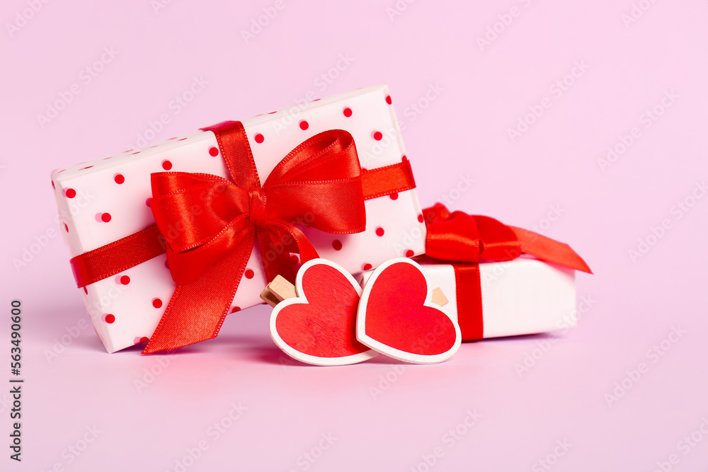 Gift boxes with beautiful bows and hearts on pink background. Valentine's Day celebration