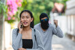 Thief Robber in mask with knife trying to snatch backpack handbag from woman victim. Bandit snatching mobile phone from a young girl crimes on city street concept.