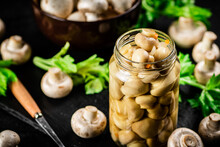Pickled Mushrooms In A Jar With Greens On A Stone Board. 