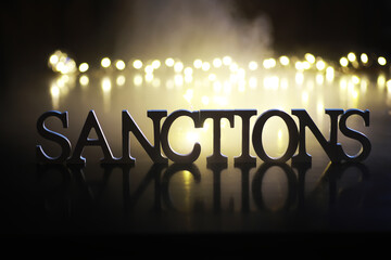 Word Sanctions made of wooden block letters with dramatic lighting and smoke