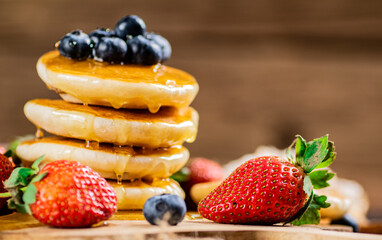 Poster - A pile of pancakes with fresh berries and honey on the table. 