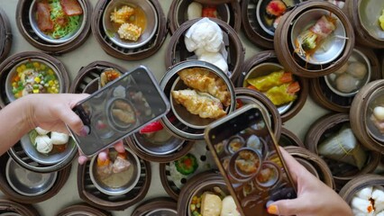 Wall Mural - Group of Asian woman hands using mobile phone taking picture Chinese food steamed dumpling in bamboo steamer at restaurant. Girl friends enjoy eating street food and travel together on summer vacation