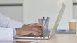 © stockbakers - Side View of African Doctor Typing on Laptop