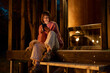 © rh2010 - Young woman sits on porch of a wooden house during a night time, enjoying nature while resting in cottage at countryside