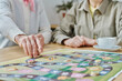 © AnnaStills - Close-up of senior woman making a move on the map, she playing board game with her friend at table