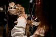 Female hairdresser stylist skilfully making hairstyle using hair dryer and round comb