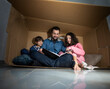 © Antonio Recena - fun in a box: father reads book to children playing inside a box