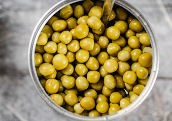 Poster - Open tin can with canned green peas with a spoon. 