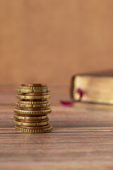 Wall Mural - Stack of coins and holy bible book with golden pages on a wooden background. Copy space for text. A closeup. Christian tithing, giving, and religious offering concept.