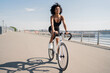 © muse studio - Happy smiling young woman curly-haired contented activity road bike riding in a sports black suit.