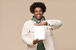 © insta_photos - Happy African American teenager student boy wearing white jacket holding pad using digital tablet showing mock up screen of tab computer technology for online education isolated on beige background.