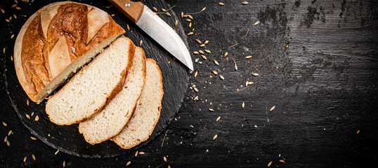 Poster - Sliced on a stone board wheat bread with grains. 