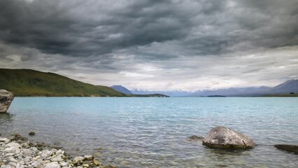 Wall Mural - Time lapse panning across Lake Tekapo in the South Island of New Zealand with snow capped mountains in the distance and dark clouds passing overhead