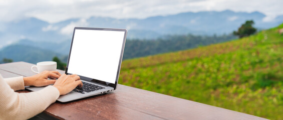 Young woman freelancer traveler working online using laptop and enjoying the beautiful nature landscape with mountain view