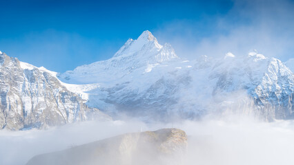 Poster - Nature. High mountain peaks above the clouds. Low clouds in the mountain valley. Clear skies and sharp rocks with glaciers. A place for hiking with a beautiful view. Lauterbrunner, Switzerland.