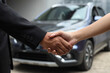 Cropped closeup image of a salesman shaking hands with his client after selling a car at the dealership.