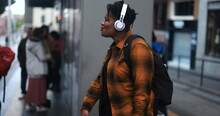 Young African American Woman Listening Music With Wireless Headphones While Waiting At Bus Station - City Lifestyle And Culture Concept