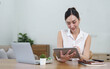 © wichayada - Young woman working on a laptop in the office. Asian businesswoman sitting at her workplace in the office. Beautiful Freelancer Woman working online at her home.
