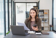 © PHAISITSAWAN - Marketing, Finance, Accounting, Planning, Businesswoman of bi nationality is talking with a customer representing a company distributor using a smartphone with laptop pen and notepad on office desk.