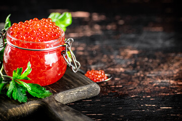 Poster - A full glass jar of red caviar on a cutting board. 