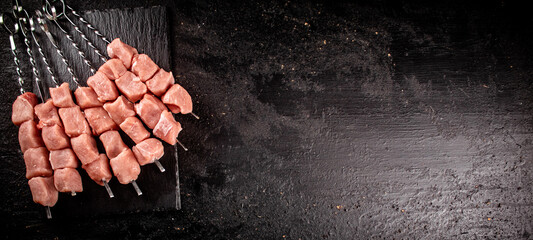 Poster - Pork kebab raw on skewers on a stone board. 