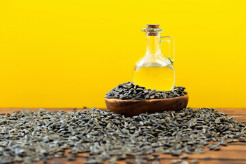 Wall Mural - oil and sunflower seeds on  wooden table on  yellow background