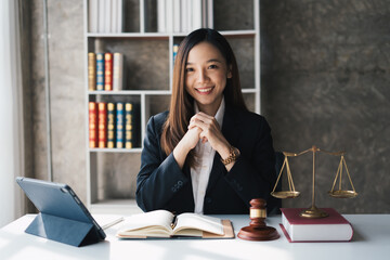 Attractive young lawyer in office Business woman and lawyers discussing contract papers with brass scale on wooden desk in office. Law, legal services, advice, Justice and real estate concept.