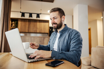 Wall Mural - a happy man is drinking his morning coffee and finishing his remote work on a laptop form home.