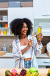 © kanpisut - Woman holding honey bottle in kitchen room.
