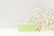 Spring minimal scene for beauty cosmetic product presentation made with green cube and wild flowers on white background.