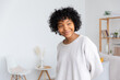 © Юлия Завалишина - Beautiful african american girl with afro hairstyle smiling at home indoor. Young african woman with curly hair laughing in living room. Freedom happiness carefree happy people concept