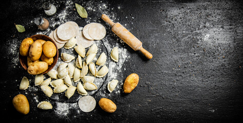 Wall Mural - Raw potato dumplings on a stone tray with rolling pin and flour. 