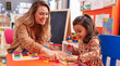 © Krakenimages.com - Teacher and toddler playing with maths puzzle game sitting on table at kindergarten