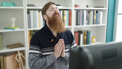 Canvas Print - Young redhead man student sitting on table praying at library university