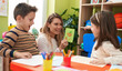 © Krakenimages.com - Teacher with boy and girl sitting on table having language lesson at kindergarten