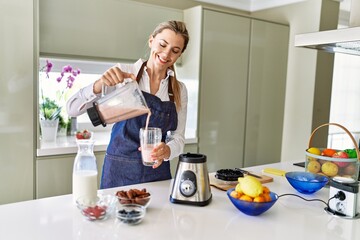 Poster - Young blonde woman smiling confident pouring smoothie on glass at kitchen