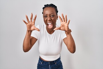 Wall Mural - Beautiful black woman standing over isolated background smiling funny doing claw gesture as cat, aggressive and sexy expression