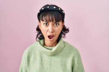 Poster - Young beautiful woman standing over pink background in shock face, looking skeptical and sarcastic, surprised with open mouth