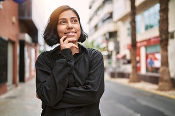 Wall Mural - Young latin woman smiling confident standing with arms crossed gesture at street