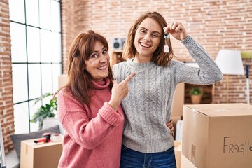 Sticker - Mother and daughter moving to a new home holding keys smiling happy pointing with hand and finger